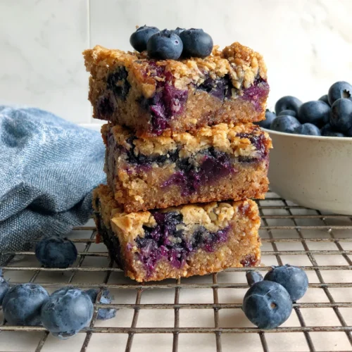 Blueberry baked oatmeal bars stacked with blueberries.
