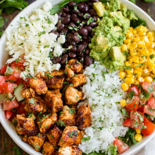 Chicken burrito bowl with chicken, beans, corn, and avocado.