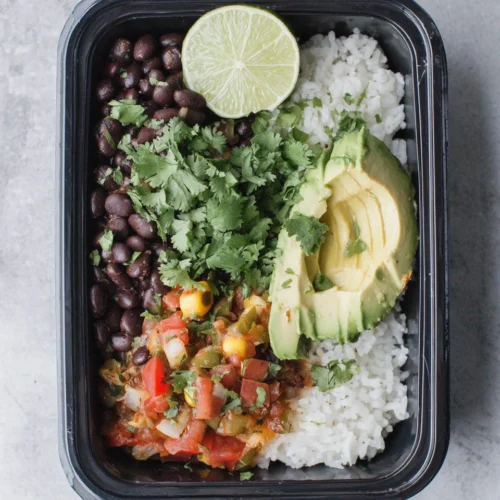 Rice and beans meal prep bowl with fresh toppings.
