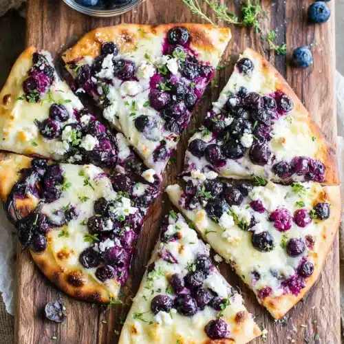 Blueberry pizza dessert featuring naan, cheeses, and blueberries.