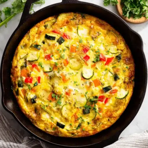 Zucchini quiche recipe with eggs in a skillet.