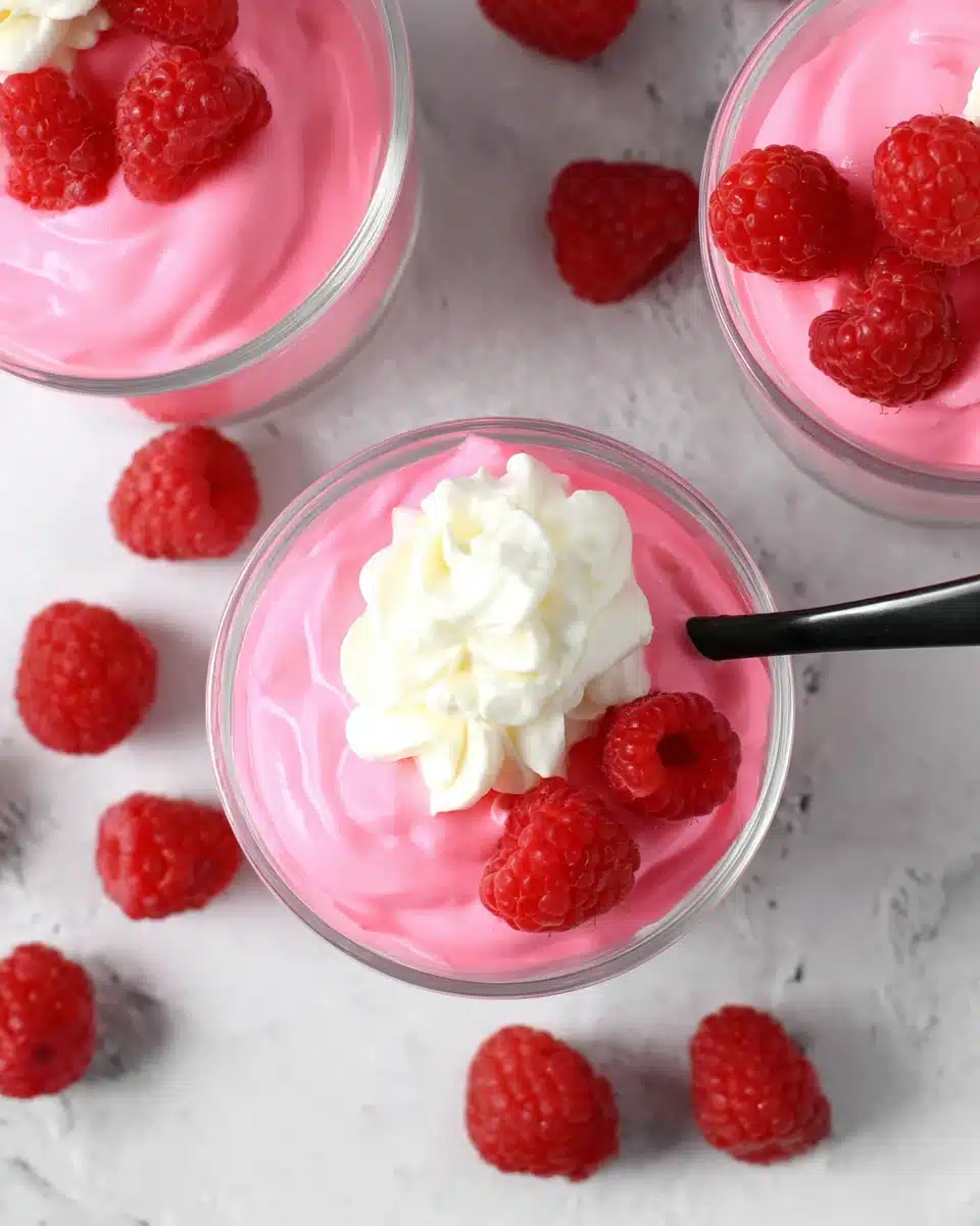 Greek yogurt jello cups with raspberries and whipped cream in glass jars