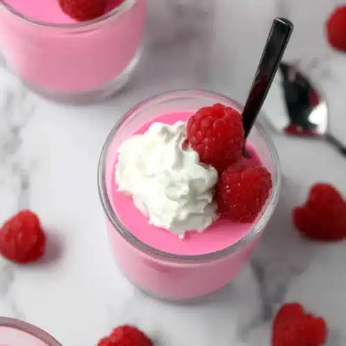 Greek yogurt jello cups with raspberries and whipped cream in glass jars
