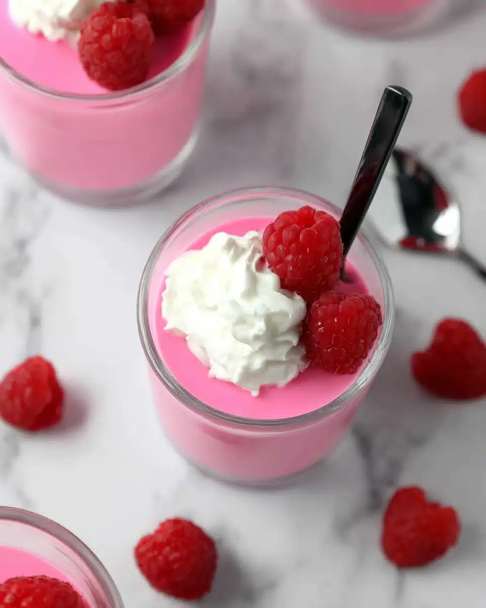 Greek yogurt jello cups with raspberries and whipped cream in glass jars
