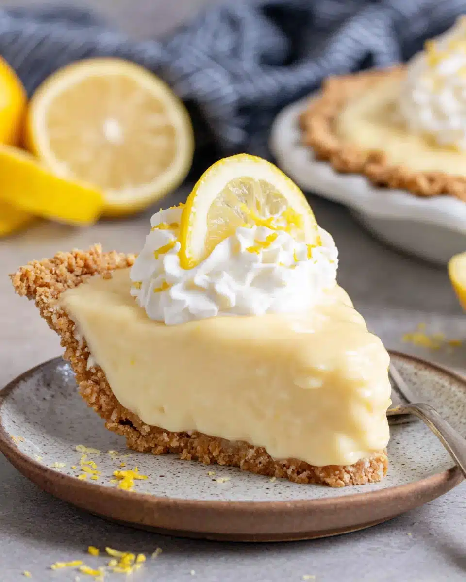 No-bake lemon curd pie slice with whipped cream and a lemon.
