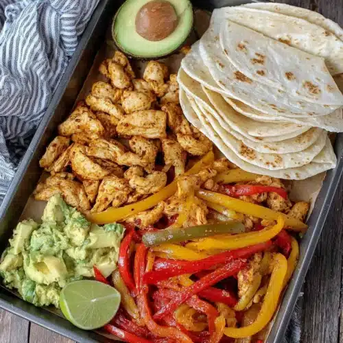 Oven baked chicken fajitas with bell peppers and tortillas.