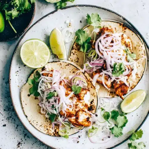 Delicious spicy fish tacos with lime, onions, and slaw.