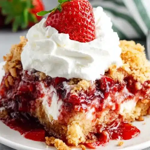Strawberry dump cake slice with whipped cream and fresh strawberry on top