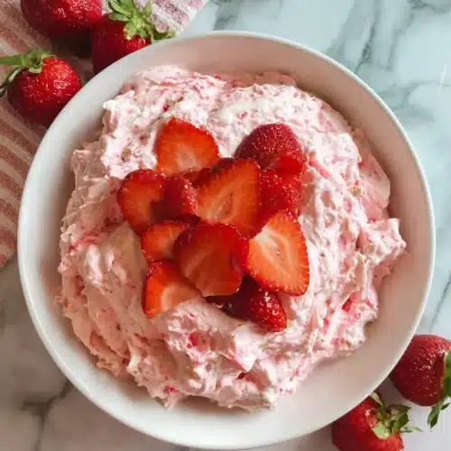 Creamy strawberry fluff salad in a white bowl with fresh strawberries