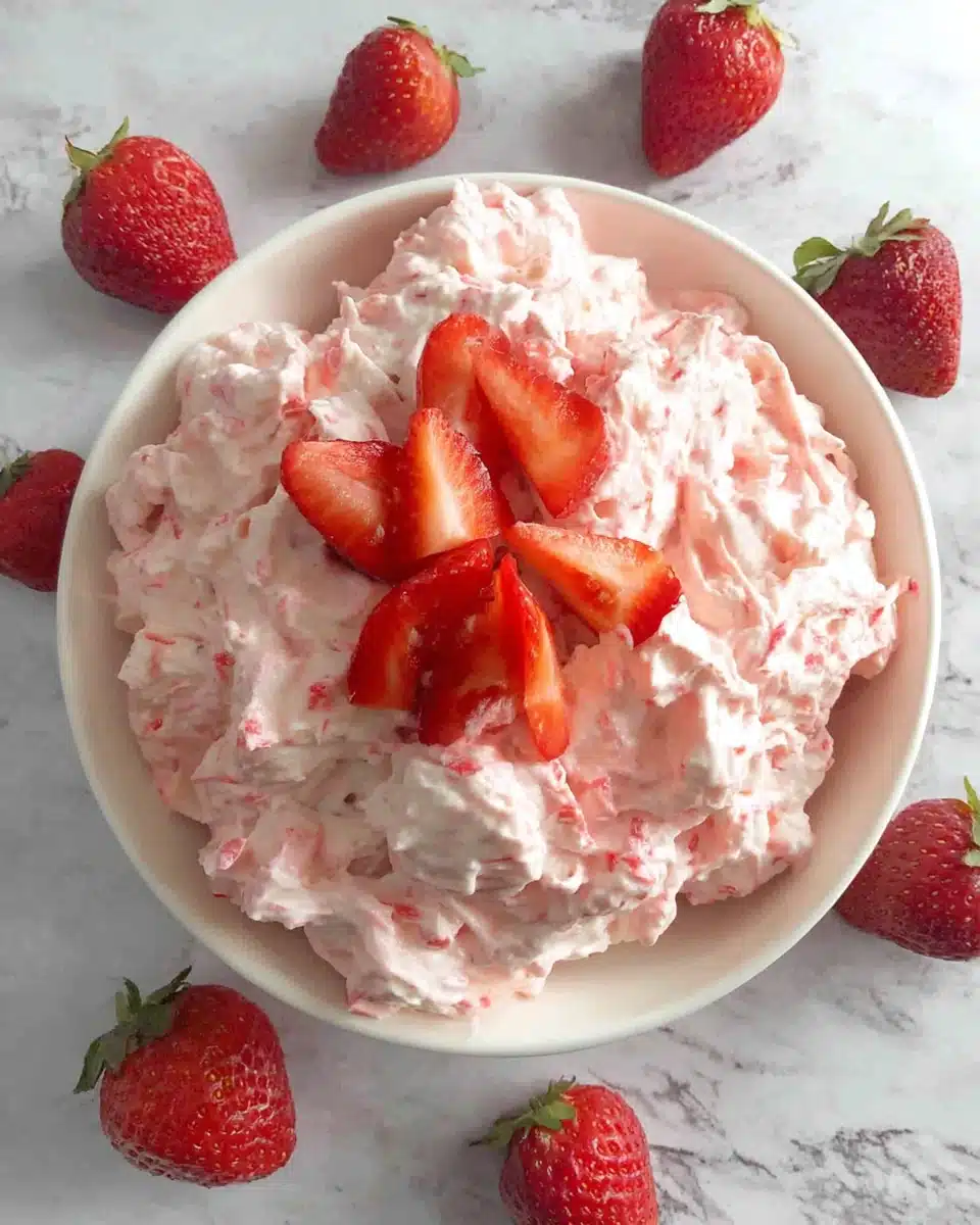 Strawberry fluff salad in a white bowl with fresh strawberries on marble