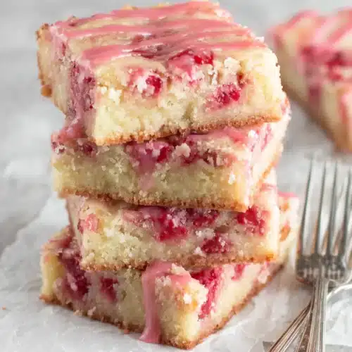 Delicious Strawberry Lemon Bars: A Sweet Treat for Everyone 1 Stack of strawberry lemon bars with pink glaze and fresh strawberries