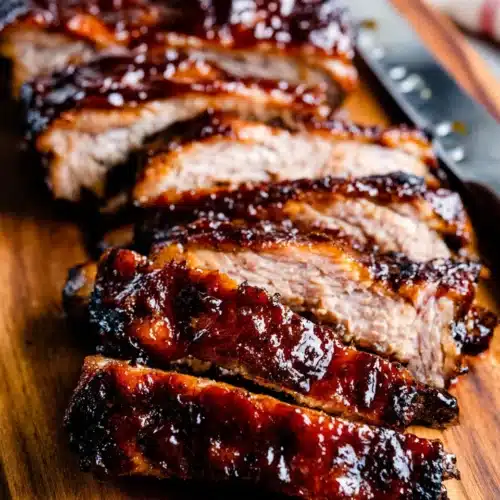 BBQ Baby Back Ribs: The Ultimate Family Favorite 1 Sliced BBQ baby back ribs on a wooden board, glazed and tender