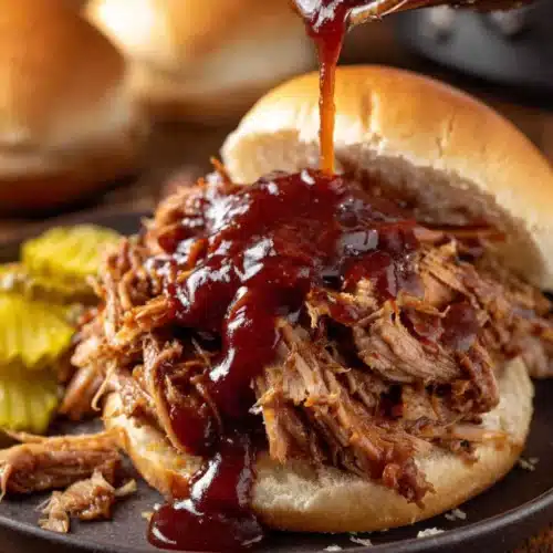 BBQ slow cooker pulled pork sandwich with sauce drizzling over top