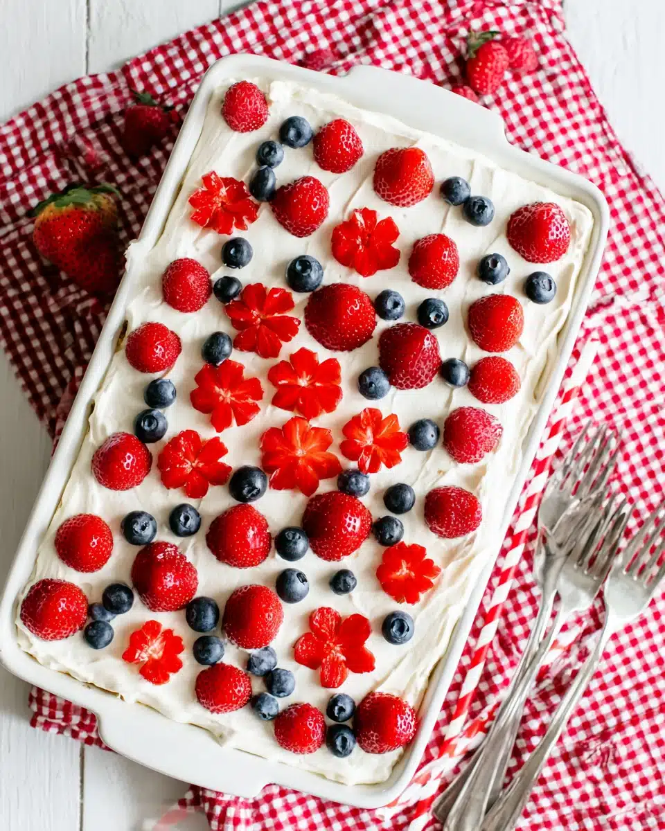 Berry tiramisu dessert topped with fresh strawberries, raspberries, and blueberries on a checkered cloth