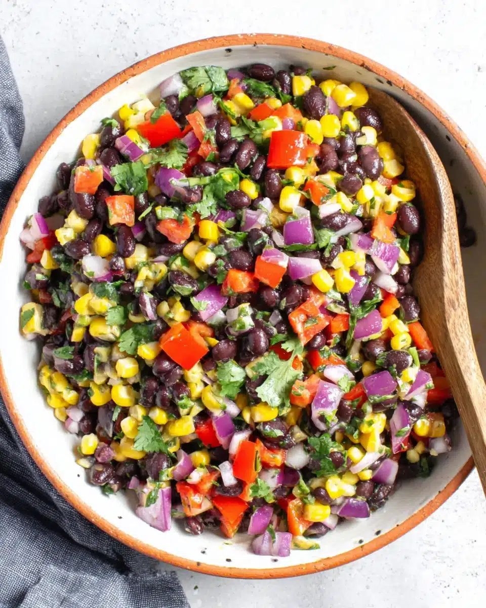 Colorful black bean and corn salad with fresh vegetables and cilantro in a white bowl