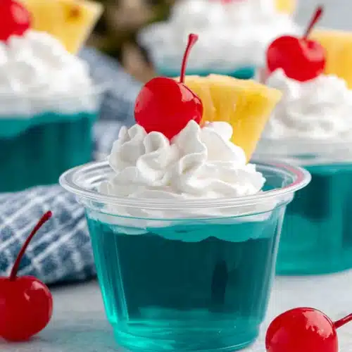 Blue Hawaiian Jello Shots: A Fun Tropical Treat 1 Blue Hawaiian jello shots with whipped cream, cherry, and pineapple garnish