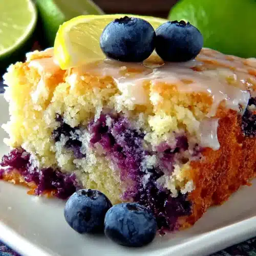 Blueberry Boyfriend Bait: Irresistibly Delicious Dessert 1 A slice of blueberry boyfriend bait cake with fresh blueberries and lemon glaze on a white plate