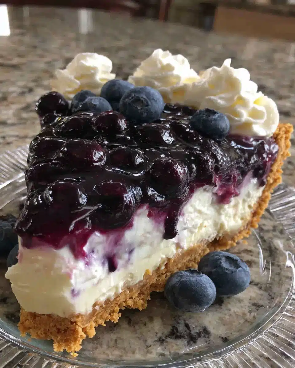 A slice of blueberry cream cheese pie with graham cracker crust and fresh blueberry topping
