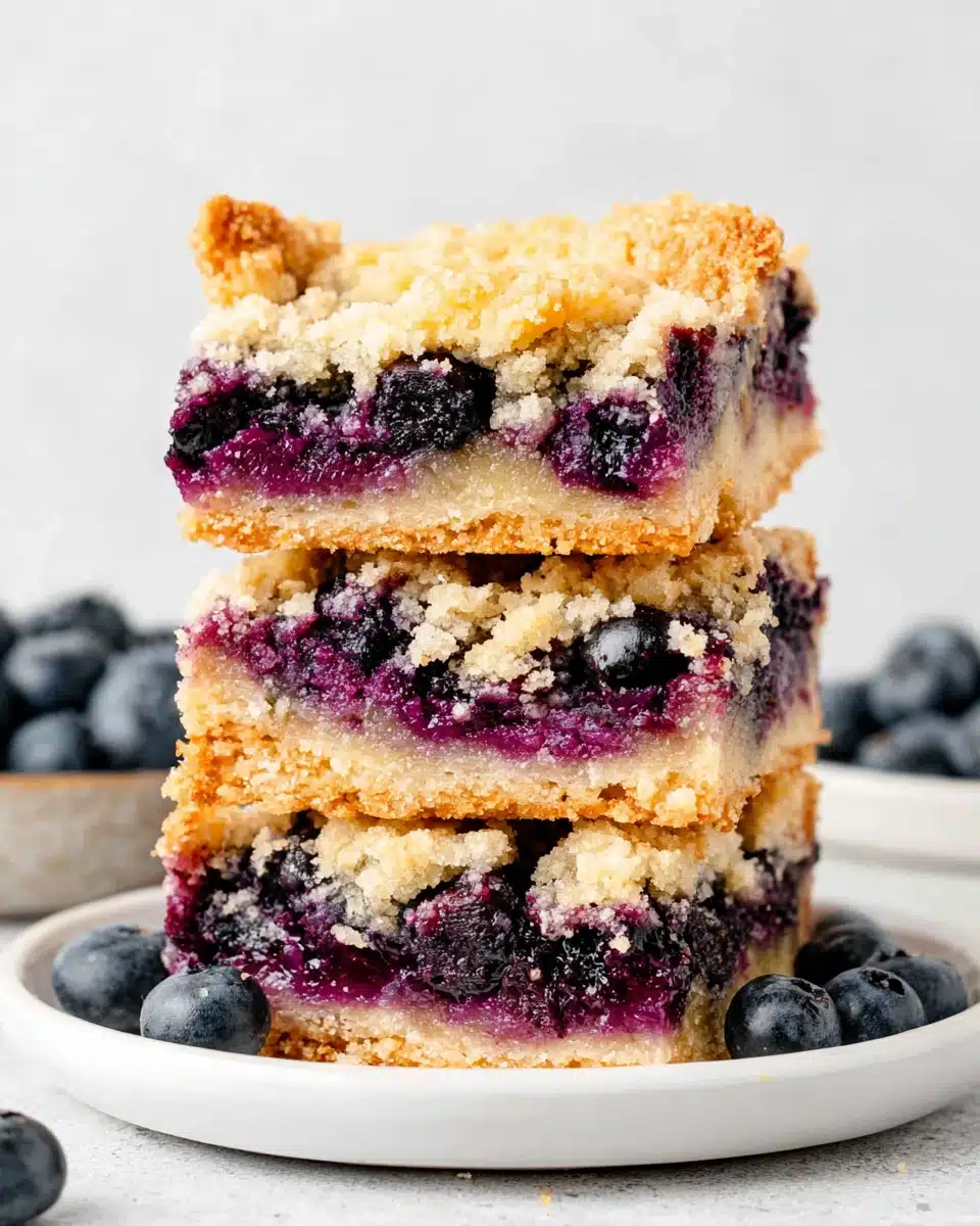 Stack of three blueberry crumble bars with golden topping and juicy berry filling