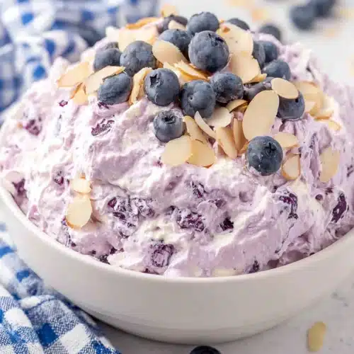 Blueberry fluff salad in a bowl with fresh blueberries and sliced almonds