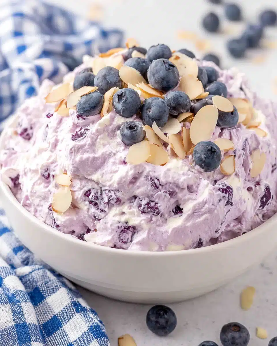 Blueberry fluff salad in a bowl with fresh blueberries and sliced almonds