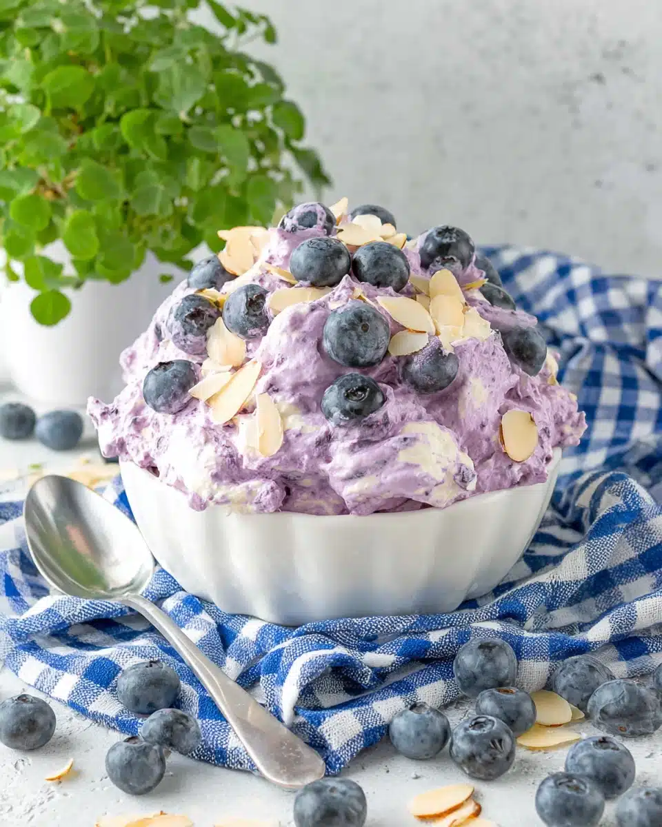 Creamy blueberry fluff salad topped with fresh blueberries and sliced almonds in a white bowl