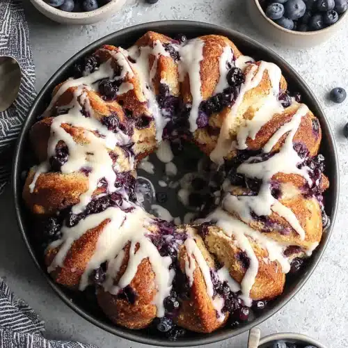 Blueberry monkey bread with white glaze and fresh blueberries on a plate