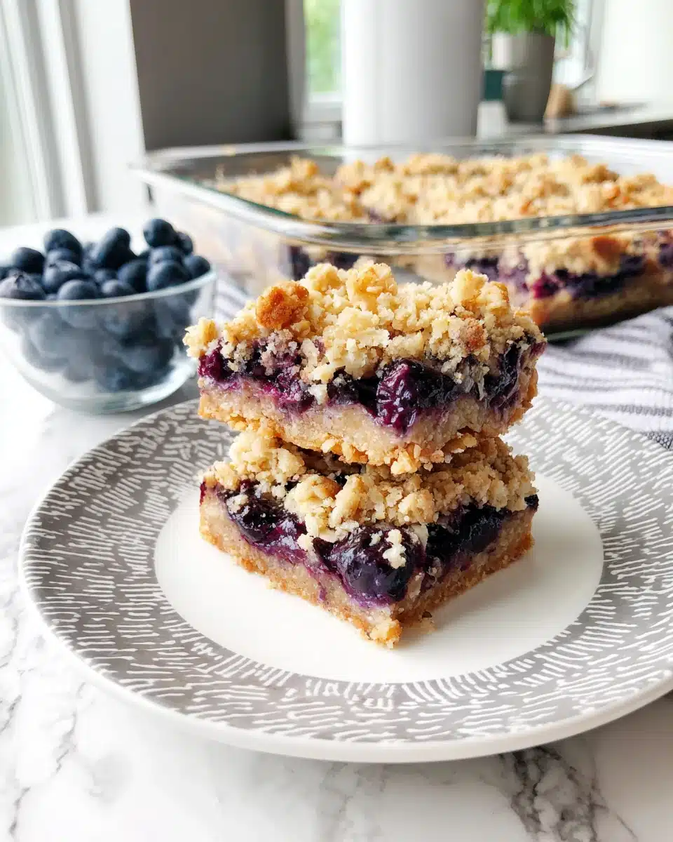 Blueberry oat crumble bars on a plate with fresh blueberries nearby
