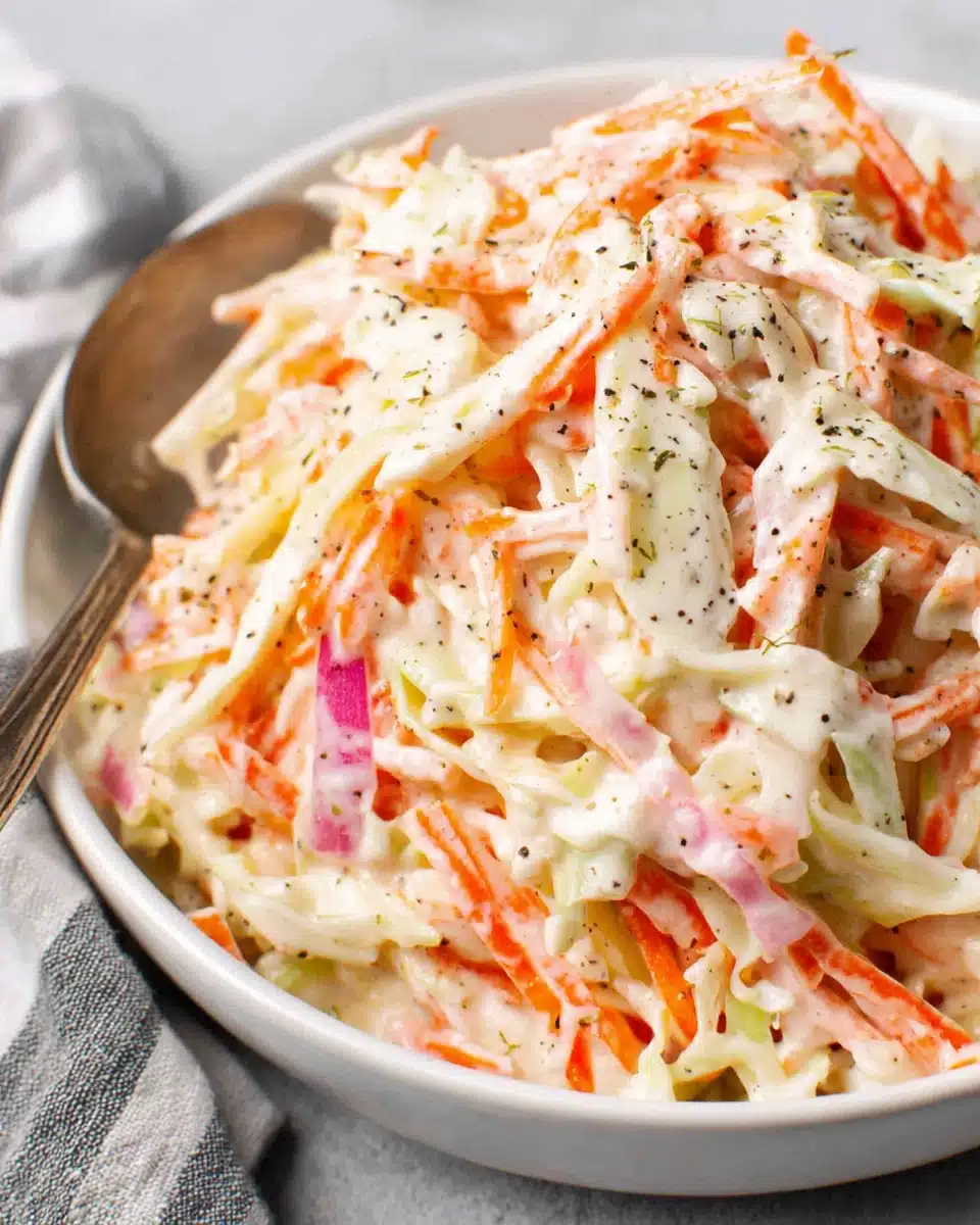 Creamy cole slaw salad with cabbage, carrots, and apple in a white bowl