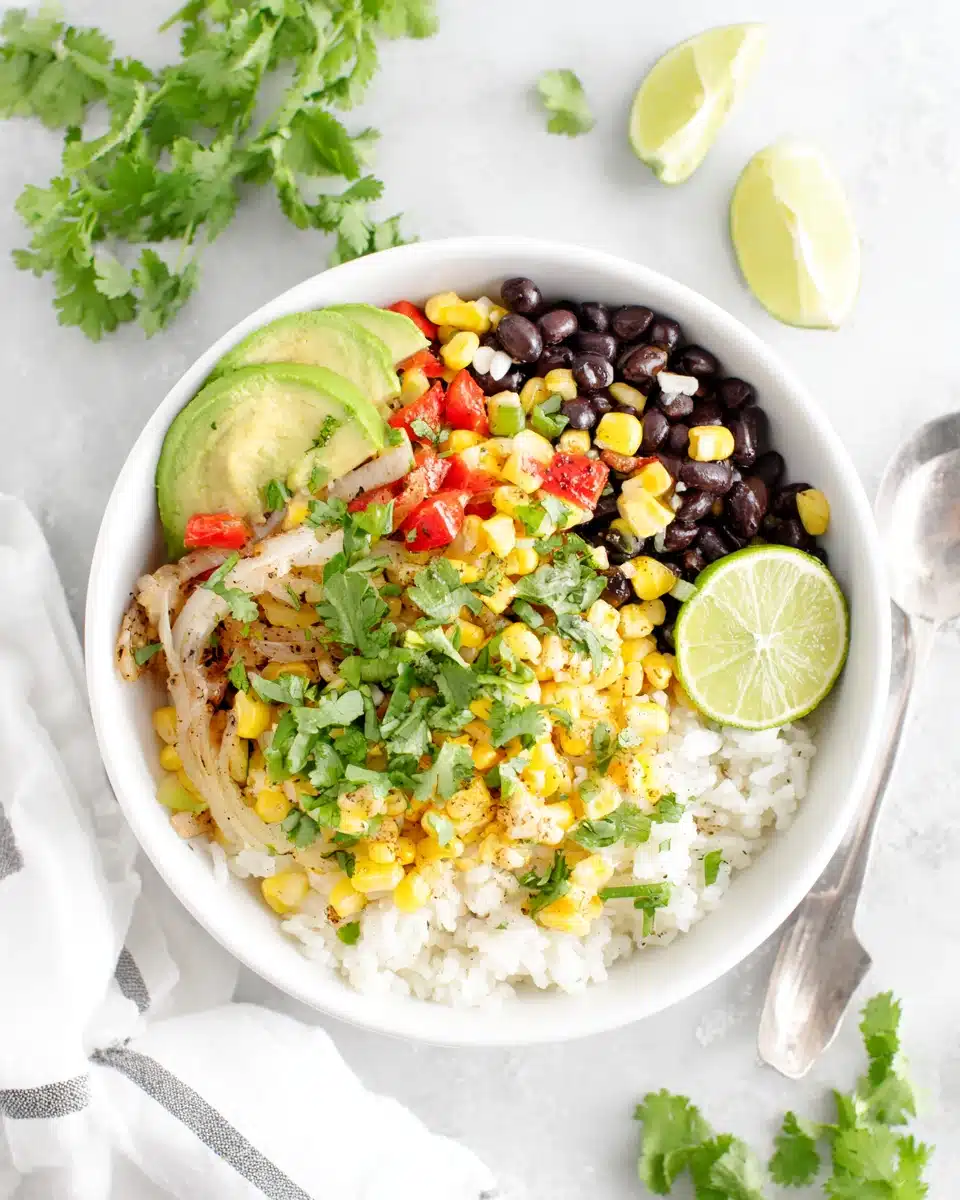 Fresh corn salsa served over rice with black beans and avocado, garnished with lime and cilantro