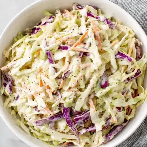 Creamy coleslaw with shredded cabbage and carrots in a white bowl