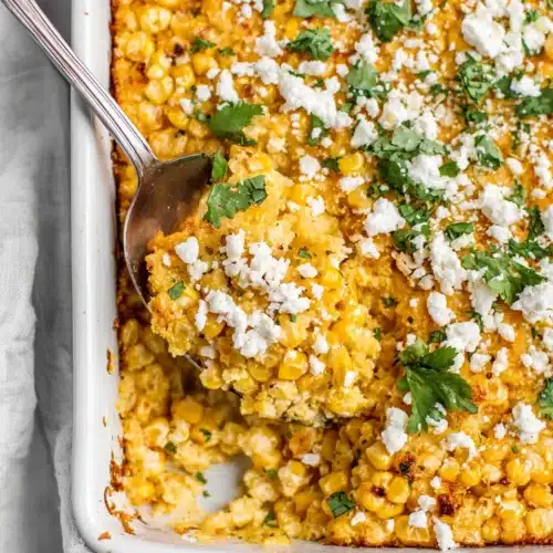 Creamy corn casserole with queso fresco and cilantro in a white dish