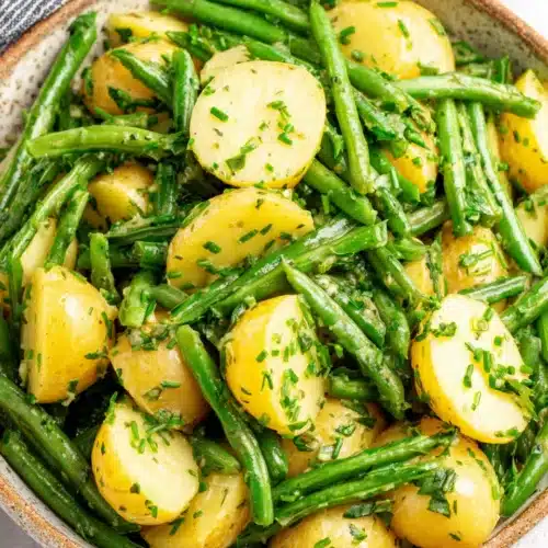 Creamy green bean potato salad with fresh herbs in a ceramic bowl
