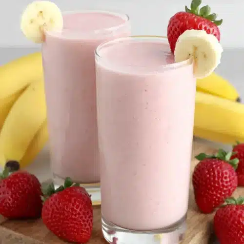Creamy strawberry banana smoothie in glass with fresh fruit garnish