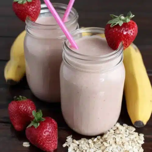 Creamy strawberry banana smoothie delight in glass jars with fresh strawberries and bananas