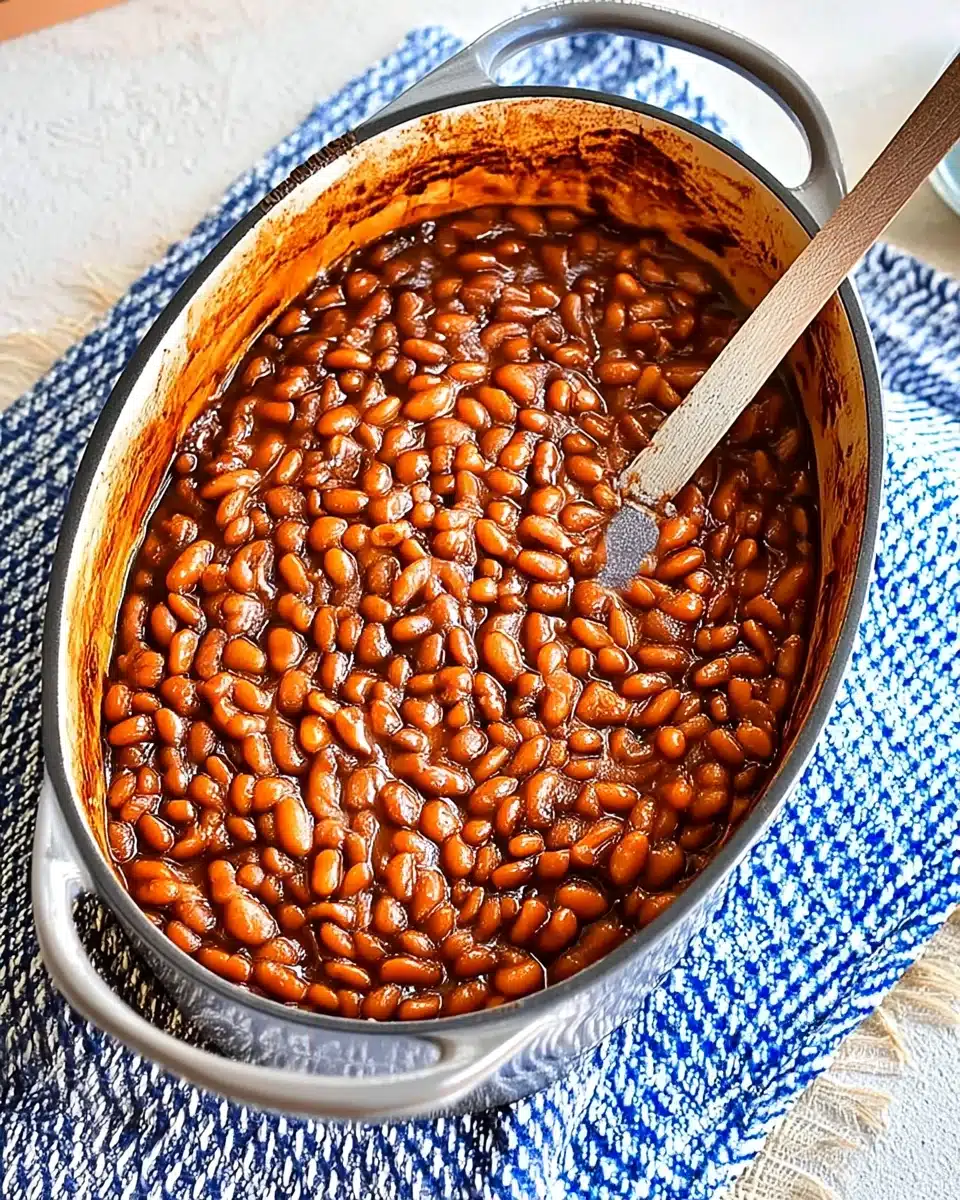 Easy baked beans in a ceramic dish with wooden spoon, ready to serve
