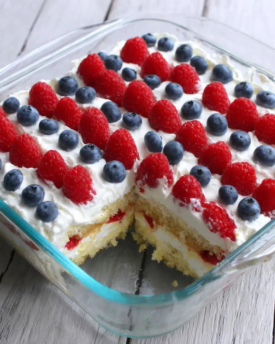 Easy flag cake with red raspberries and blue blueberries arranged in American flag design on white whipped topping