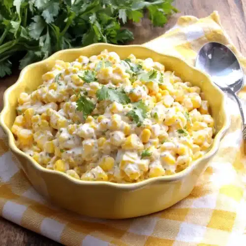 Creamy elote corn salad with cilantro in a yellow bowl