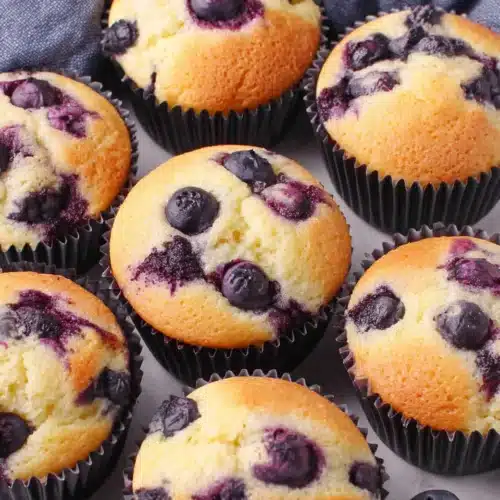 Fluffy Greek yogurt blueberry muffins with juicy berries in black liners