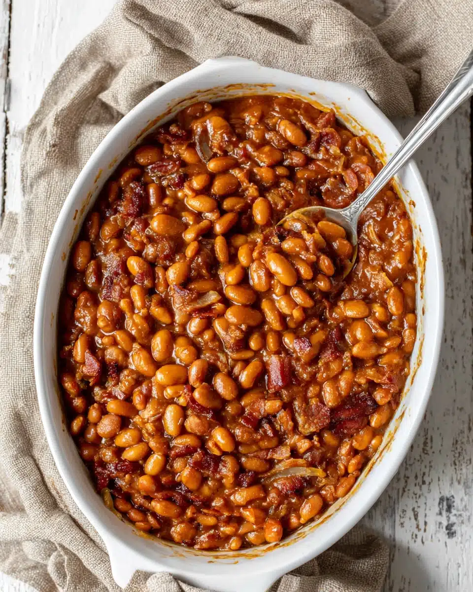 Healthy Baked Beans Recipe in White Dish Healthy baked beans in a white dish with a spoon, rich sauce and beans visible