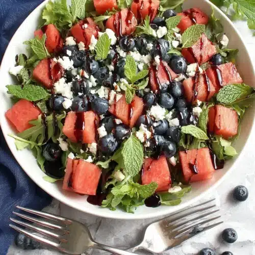 July 4th salad with watermelon, blueberries, feta, and mint in a white bowl