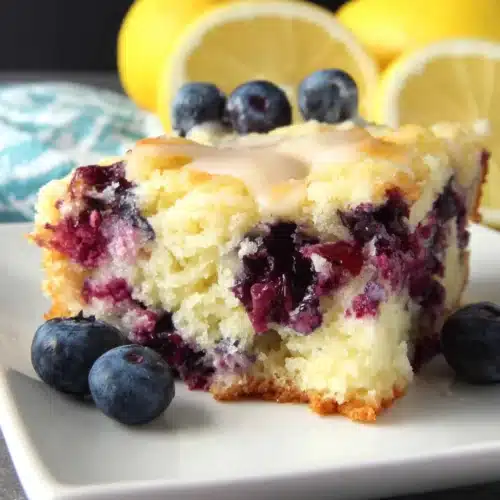 Lemon blueberry breakfast cake slice with fresh blueberries and lemon halves