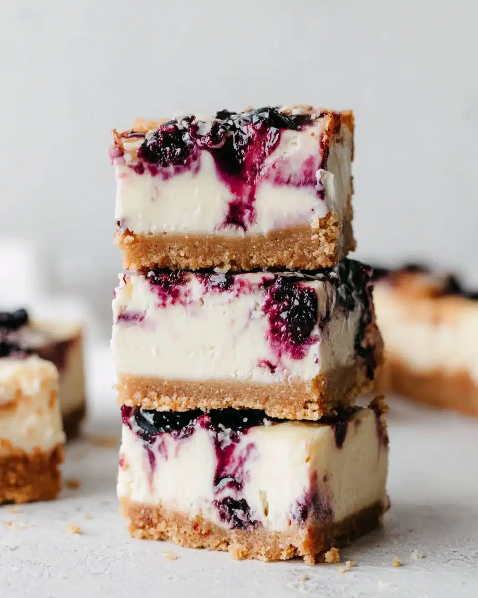Stacked lemon blueberry cheesecake bars with creamy filling and blueberry swirl
