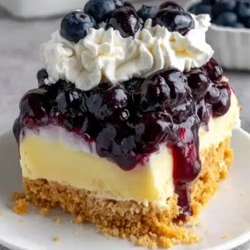 Lemon Blueberry Dream Dessert: A Delightful Treat 1 Lemon blueberry dream dessert slice with graham cracker crust, blueberry layer, creamy lemon filling, and whipped topping
