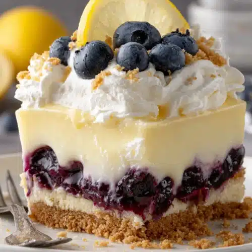 Lemon blueberry lush dessert slice with graham cracker crust, creamy layers, and blueberry topping