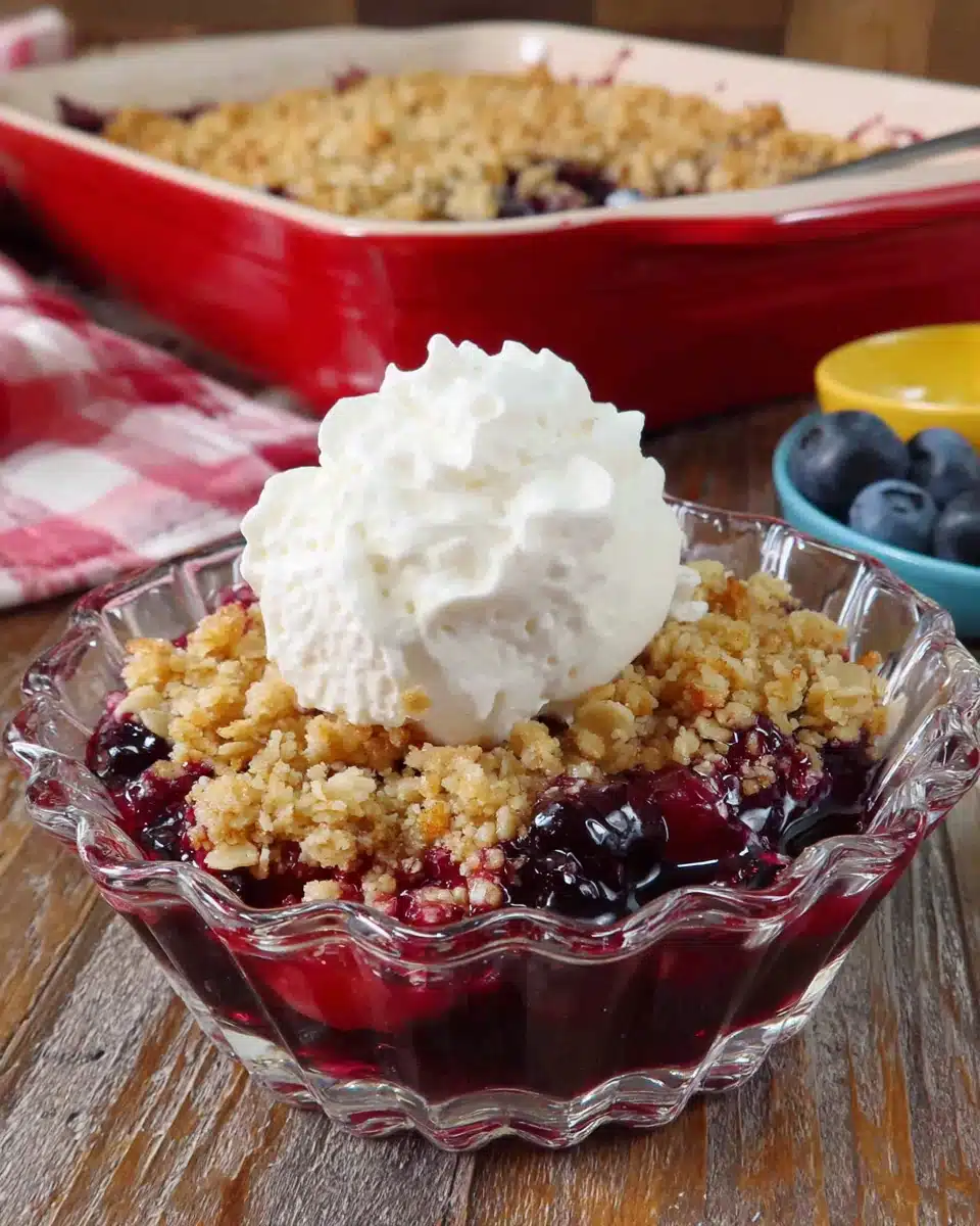 Mini blueberry crisp in a glass dish with whipped cream