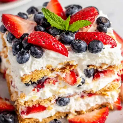 No bake berry icebox cake with layers of graham crackers, cream, strawberries, and blueberries
