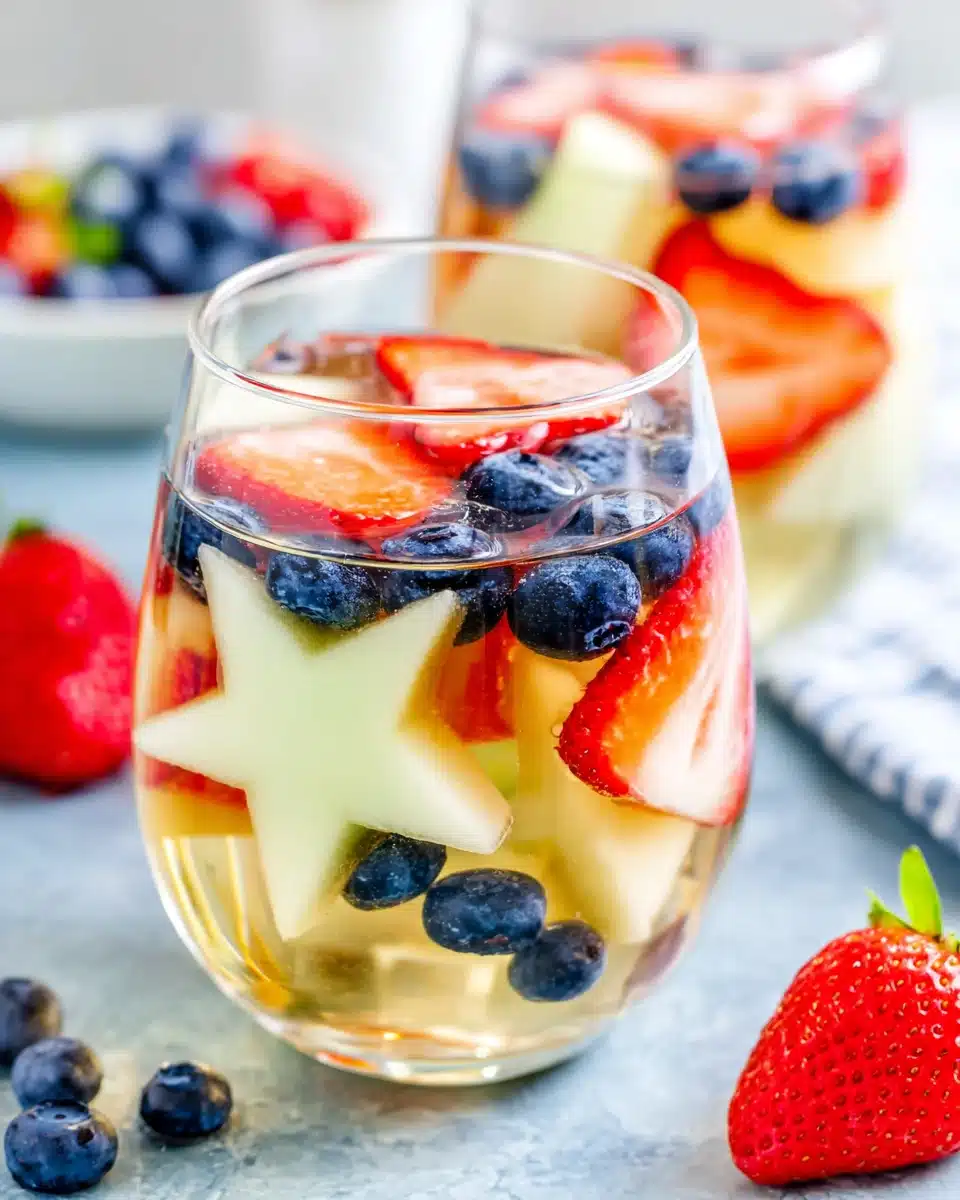 Patriotic sangria with star-shaped melon, strawberries, and blueberries in a glass