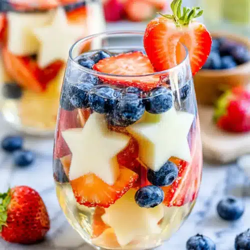 Patriotic sangria with strawberries, blueberries, and star-shaped melon in a glass