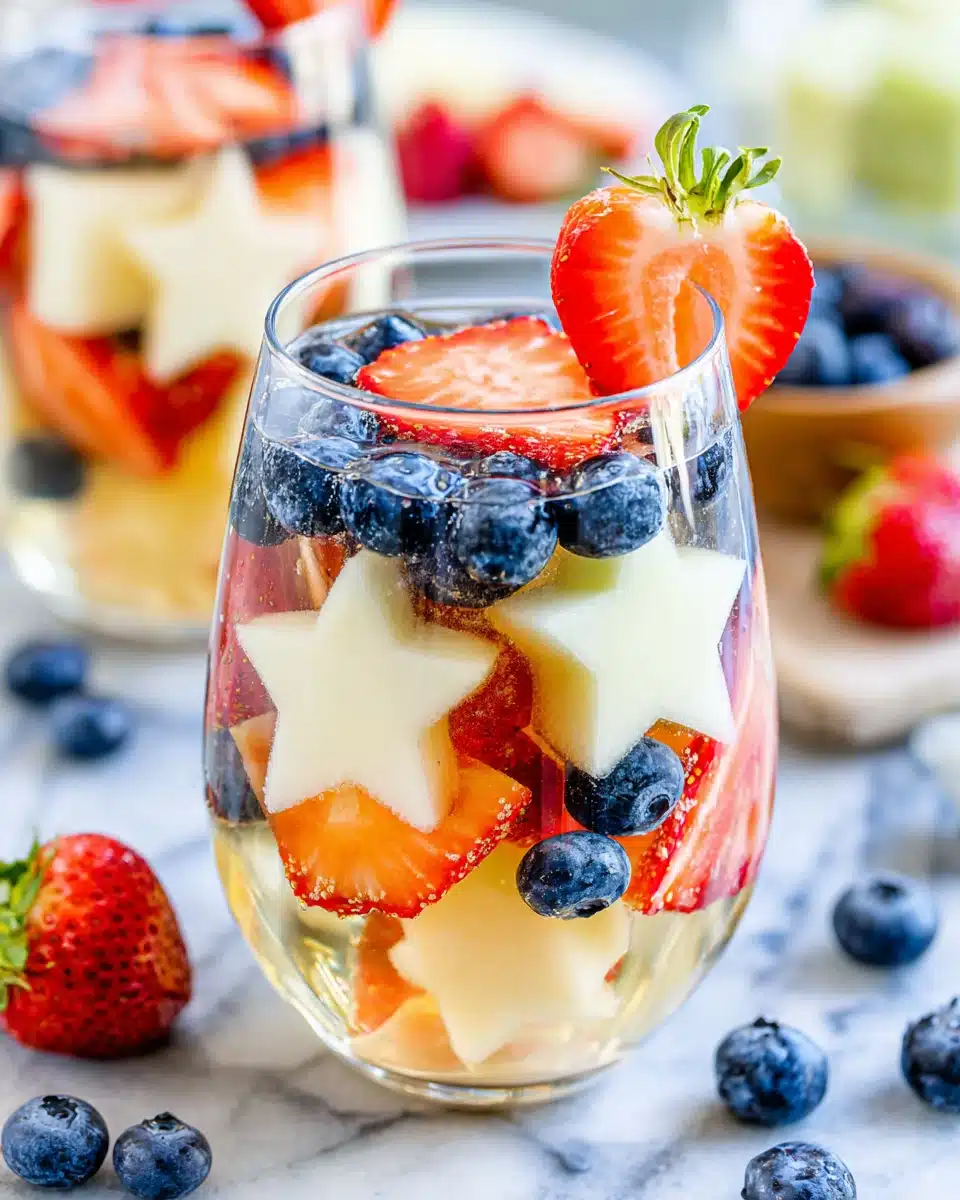 Patriotic sangria with strawberries, blueberries, and star-shaped melon in a glass